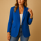 Femme portant le blazer cintré bleu ouvert sur un top blanc et un jean