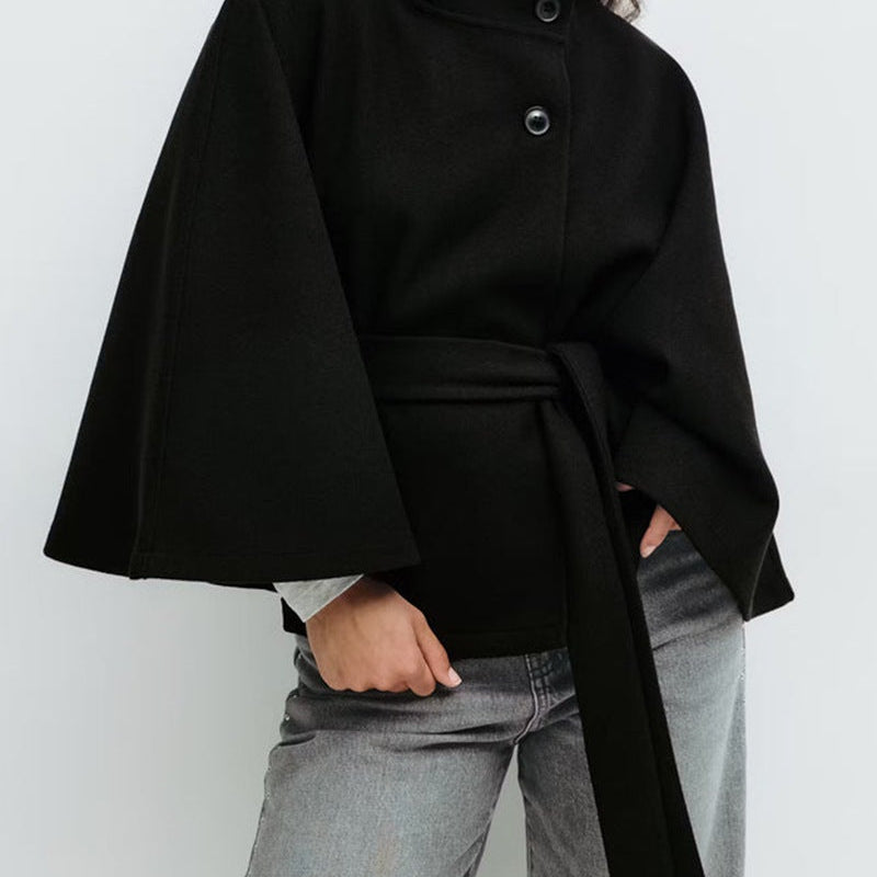 Cape noire ceinturée portée avec un jean gris