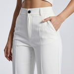 Détail de la taille haute, du bouton et de la poche du pantalon blanc